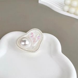 Close-up of heart-shaped phone grip featuring pearl texture and iridescent accents