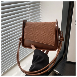 Detail view of woven texture pattern and knot handle on a dark brown square handbag