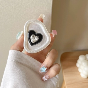 Detail of heart-shaped phone grip with pearl finish base and sparkling center gem