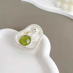 Detail of flower phone grip with green gemstone, pearl, and white rose on a cloud tray