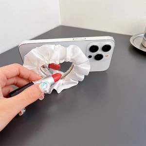 Close-up of heart-shaped lace mirror phone grip used for makeup with a silk fabric texture