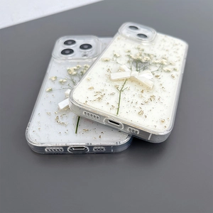 Detail view of iPhone case with dried flowers, gold foil, and white resin bow decoration