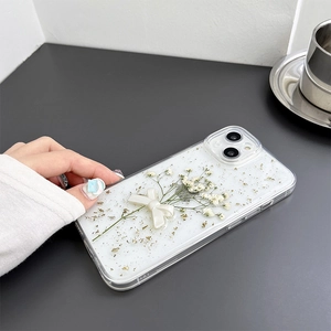 Detail of iPhone case with real dried flowers, white resin bow, and gold foil accents