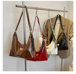 Detail of vintage glossy leather underarm bag with metal logo and tennis racket charm