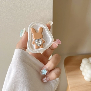Close-up of hand holding a cute brown rabbit phone stand with a large heart crystal
