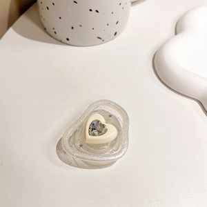 Detail of heart-shaped glitter phone grip with rhinestones on a white desk setup