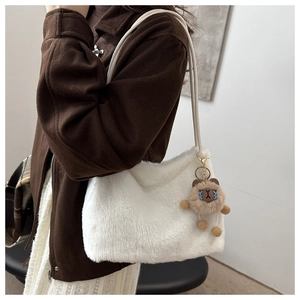 Detail of white fluffy faux fur tote bag with a cute brown plush pendant on a strap