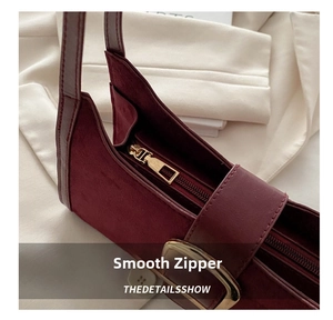 Detailed close-up of smooth gold zipper and texture on wine red leather shoulder bag