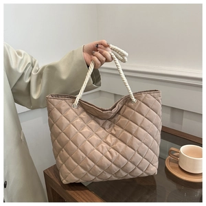 Detail of quilted khaki tote bag featuring woven rope handles and metal grommets
