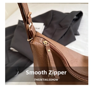 Detail view of smooth gold zipper and caramel brown leather texture on shoulder bag