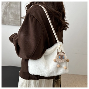 Détail d'un sac à bandoulière en peluche blanche avec un charm ours brun mignon