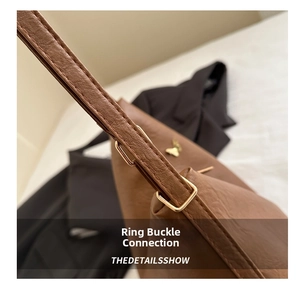 Detail view of gold buckle connection on brown pebbled leather shoulder bag strap