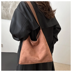 Detail view of brown suede hobo bag with sleek leather strap on model shoulder