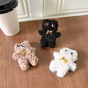 Detail of plush cat ear phone grips in brown, black, and white with golden bowknots