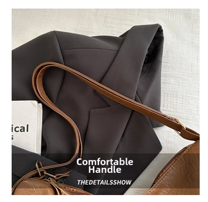 Detail of brown leather tote bag showing fine texture and bronze adjustable buckle