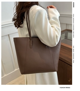 Detail of brown lychee grain leather tote with embossed logo and slim shoulder straps