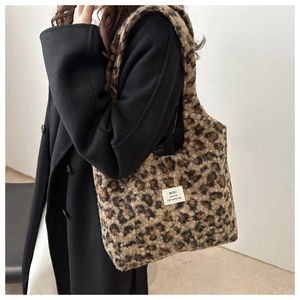 Detail view of leopard print plush bucket bag with brand label on a black winter coat