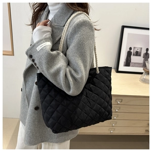 Détail du fourre-tout noir en nylon matelassé avec des poignées en corde de coton