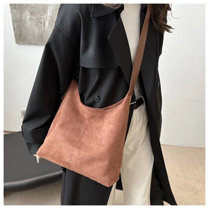 Detail of a large brown suede tote bag featuring vertical stitching and leather straps