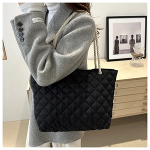 Détail du sac fourre-tout matelassé noir avec des poignées en corde blanche tressée