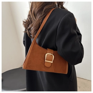 Detail of vintage brown suede crescent underarm bag with large gold metal buckle decoration