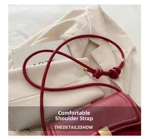 Detail of red leather shoulder bag with knotted strap and gold metal hardware accents