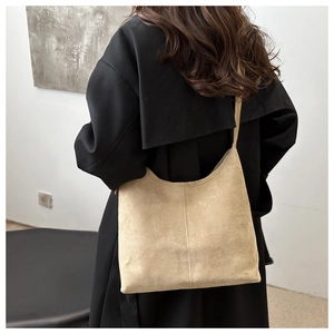 Close-up of beige suede tote bag with middle stitching detail shown on shoulder