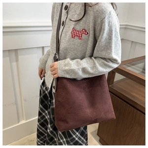 Detail view of burgundy faux suede tote bag with brown adjustable strap and metal hardware