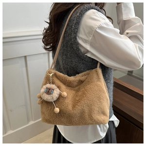 Détail d'un sac bandoulière en peluche marron avec un pendentif mignon sur mannequin