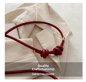 Detail of red leather strap with knotted design and gold metal cylindrical buckle