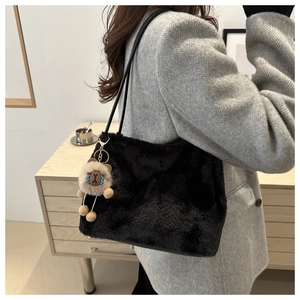 Detail of a black faux fur tote bag featuring a cute plush bear charm and long straps