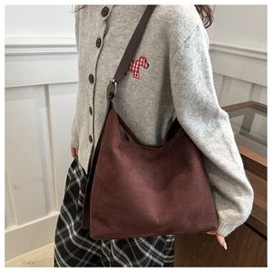 Side view of a vintage dark brown suede tote bag worn on shoulder by a model