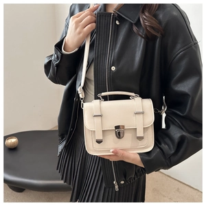 Detail of off-white mini square crossbody bag with silver twist lock on leather jacket