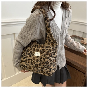 Detail of plush leopard print shoulder bag with brand woven label on soft faux fur texture