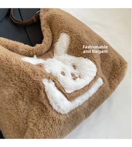 Detail view of brown plush tote bag with white rabbit embroidery and leather strap
