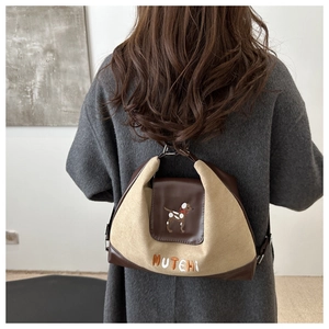 Detail of canvas and faux leather tote bag with embroidered dog and MUTEHI text