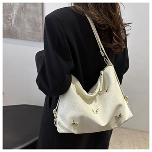 Detail of cream oversized tote bag with gold butterfly accents on pleated leather texture
