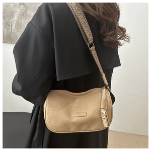 Detail of khaki crossbody bag featuring a woven ethnic shoulder strap and soft texture