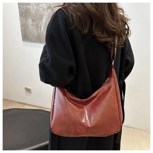 Detail of dark red vintage faux leather tote bag on black wool coat for women