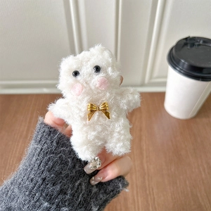 Close-up of white plush bear phone grip with golden metal bow on a wooden desk