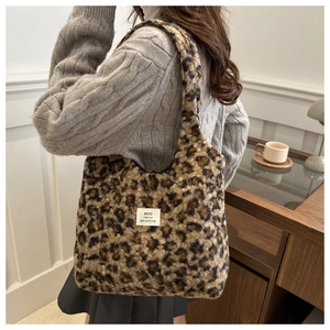Detail view of leopard print plush tote bag with white woven label on fuzzy texture