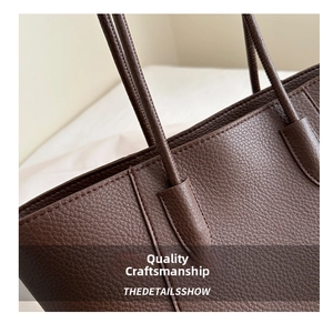 Close-up of litchi texture leather and fine stitching on a dark brown tote bag