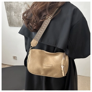 Detail of beige Boston bag with textured leather and wide geometric pattern strap