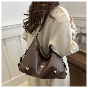 Detail of brown faux leather tote featuring golden butterfly accents and litchi texture
