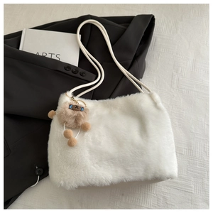 Détail du sac fourre-tout en peluche blanche avec charm ours brun sur un blazer noir