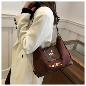 Detail of retro brown suede bag with dog embroidery on a model wearing white blazer