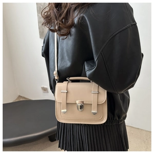 Detail of a beige PU leather crossbody bag with silver hardware on a fashion model