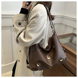 Detail of dark brown faux leather tote with decorative gold butterfly metal accents
