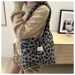 Detail of plush leopard print tote bag with white woven label on soft faux fur surface