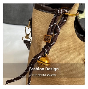 Macro shot of khaki woven fabric with dark brown leather and an engraved gold metal bead